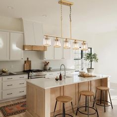 a kitchen island with stools and lights hanging from it's ceiling over the counter