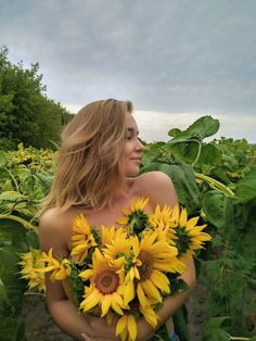 a woman standing in the middle of a field with sunflowers on her chest