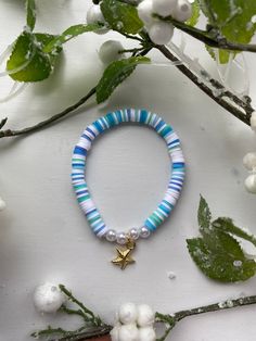 a bracelet with blue beads and a gold star charm on it, surrounded by white flowers