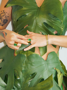 a woman in a green dress with her hands on the palm leaves