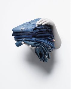 a white mannequin's head with blue jeans stacked on top of each other