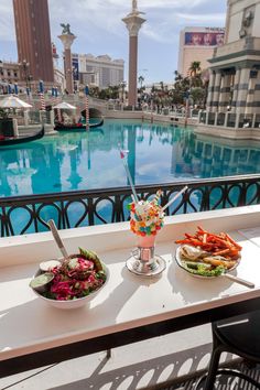 two plates of food sit on a balcony overlooking a pool