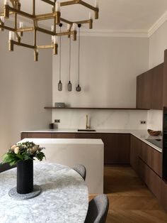 a vase with flowers sitting on top of a table in a kitchen next to an oven