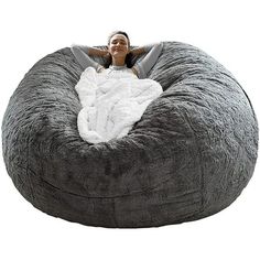 a woman laying on top of a large bean bag chair with a blanket over it