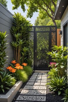 an outdoor garden with plants and flowers on the side of the house, along with a black gate