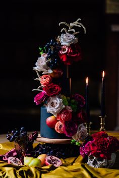 a wedding cake with flowers and fruit on the top is surrounded by other food items