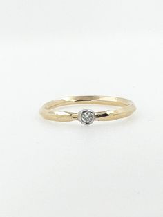 a yellow gold ring with a diamond on the bottom and a small white diamond in the middle