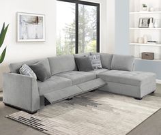 a living room with a large gray sectional couch and white rugs on the floor