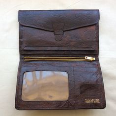 Vintage brown  leather bi-fold wallet, 1970s W 4 inches  10 cm H 6.5 inches  16.5 cm Inside left, tab and strap that give access to complete width and length of wallet back compartment. Three slip in pockets. Central metal zip gives access to another complete width and length of wallet back compartment. Right side has one slip in pocket for notes,  plus card pocket and stamps pocket, plus one vinyl window pocket.Rich dark brown textured leather with foil markings, made in China, real leather. Ve Retro Bifold Wallets With Coin Pocket, Vintage Trifold Wallet With Coin Pocket For Travel, Vintage Leather Trifold Wallet With Coin Pocket, Vintage Leather Trifold Wallet For Travel, Retro Bifold Wallet For Everyday Use, Retro Leather Wallet With Coin Pocket, Vintage Wallets With Snap Closure For Everyday Use, Vintage Travel Wallets With Coin Pocket, Vintage Wallets With Snap Closure