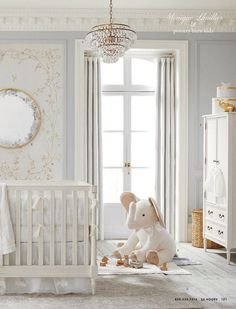 a baby's room with a white crib, chandelier and an elephant stuffed animal