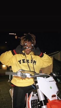 a man with dreadlocks sitting on a motorbike in the street at night