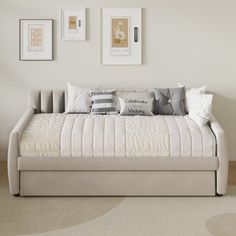 a daybed with pillows and pictures on the wall above it in a living room