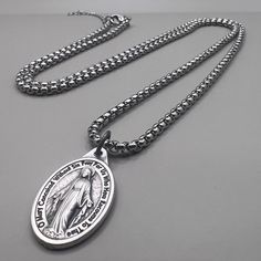 Adorning a 30cm chain, this necklace features a pendant of profound significance, the Miraculous Medal. This iconic piece of religious jewelry showcases the image of the Virgin Mary, radiating grace and maternal love. It symbolizes the divine blessings, intercession, and protection attributed to the Blessed Mother. Wearing the Miraculous Medal close to your heart is more than just a piece of jewelry; it is a tangible connection to the spiritual realm. Devotees believe in the miraculous powers associated with this sacred emblem, turning to it for comfort, guidance, and hope in times of need. The 30cm chain ensures that the Miraculous Medal rests gracefully against the wearer's chest, allowing them to carry the faith and blessings it represents with them wherever they go. This necklace not o Spiritual Necklace With Miraculous Medal For Commemoration, Spiritual Commemoration Necklace With Round Pendant, Spiritual Round Pendant Necklace For Commemoration, Spiritual Crucifix Necklace For Memorial, Miraculous Medal Pendant Necklace For Memorial, Miraculous Medal Pendant Necklace For Memorials, Spiritual Stainless Steel Locket Necklace, Spiritual Engraved Pendant Chain Necklace, Spiritual Pendant Necklace For Memorial