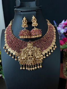 Goddess Lakshmi Bottu Pendent Grand Neckless with Earrings/ Temple Jewelry/ Antique gold finish / Cluster Maroon Beads / Indian Jewelry This is a grand Necklace set featuring Goddess Lakshmi surrounded by elephants and Maroon  beads and gold coins with Goddess Lakshmi form an impressive collar, while kemp stones add  DETAILS: Includes one necklace and two earrings. Necklace: Approx 9 inches. Adjustable length. Rope closure. Weighs 5.6 oz (159 g).  Earrings: 2 inch(es) long. Earring set weighs 1. Luxury Hallmarked Temple Jewelry Danglers, Temple Jewelry Sets With Dangling Beads For Celebrations, Festive Jewelry Sets With Dangling Beads For Celebration, Temple Jewelry With Dangling Beads For Diwali, Diwali Temple Jewelry With Dangling Beads, Temple Jewelry Sets With Dangling Beads For Wedding, Festive Jewelry Sets With Dangling Beads For Festivals, Festive Jewelry Sets With Dangling Beads, Gold Fusion Jhumkas With Peacock Design