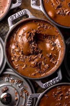 several chocolate pots filled with different types of desserts on top of metal pans