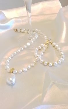 This timeless, elegant pearl necklace is handmade of white freshwater pearls and shows off a large center baroque pearl. the baroque pearl is a 16mm drop, cream color austrian crystal core pearl which makes it harder and high luster. The freshwater  pearls are off round shape, creamy white, high luster and are accented by tiny  gold spacer beads all are secured by a gold hammered bail. This beauty measures seventeen inches and the baroque pearl sits just below the hollow in your neck. Consider this lovely piece as a gift for mom, your maid of honor, a grad,  gift.,Prom or to wear for a formal event even a night on the town. Pearls  are always classy and  exude sophistication, the perfect accessory to your little black dress. Shown is a matching bracelet also available, listed separately at White Freshwater Pearl, Bridal Party Gifts, Bridal Jewelry Sets, Matching Bracelets, Baroque Pearls, Pearl Pendant, Spacer Beads, Gift Necklace, Handmade Necklaces