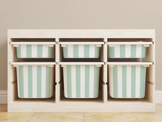 a wooden shelf with four green and white striped bins