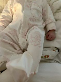 a baby laying on top of a bed covered in white blankets