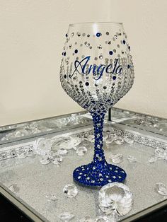 a blue wine glass sitting on top of a tray with silver and blue beads around it