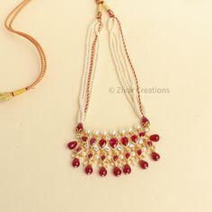 This unique Tanmani features 7 white-colored stones, complemented by pearls woven into the necklace strings. Red drop shape beads add a charming touch, enhancing the beauty of this exquisite design. Inspired by the Peshwa style, this necklace is a popular choice among women in Maharashtra. Crafted with 3mm pearls strings intricately woven and decorated with Jeri, the necklace comes with an adjustable thread. Please note that this is our handmade creation. You may also consider pairing it with ou Affordable Necklace For Puja And Diwali, Traditional White Kundan Necklace With Polished Beads, Festive White Kundan Necklace With Polished Beads, Handmade Pearl Bridal Necklace For Festivals, Traditional White Ruby Bridal Necklace, Handmade White Kundan Beaded Necklace, Handmade White Kundan Beaded Necklaces, Traditional Bridal Necklace With Dangling Beads As Gift, Red Pearl Drop Jewelry For Festive Occasions