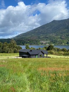 a large house sitting in the middle of a lush green field next to a lake