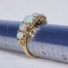 "This Victorian ring was handcrafted in England around 1900. It's a glimmery little stunner featuring five round cabochon opals patterned with 10 rose cut diamonds. The largest opal can be found at the center of the ring face, it measures 5.3 mm in diameter and 3.3 mm in depth. This piece is a size 8.25 and it weighs 4.5 grams. The ring face measures 7.5 x 22.5 and it sits 5.4 mm off the finger. It bears the gold purity mark, \"18 C\". Opals look like the universe and all her colors inside one t Victorian Style Opal Round Rings, Victorian Style Round Opal Ring, Victorian Round Opal Ring Hallmarked, Antique Multi-stone Opal Ring For Anniversary, Victorian Hallmarked Opal Ring, Opal Ring With Rose Cut Diamonds For Anniversary, Victorian Yellow Gold Opal Jewelry, Victorian Opal Ring For Wedding, Vintage Round Cabochon Opal Ring