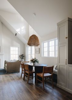 a dining room table and chairs in front of an open living area with wood flooring