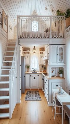 a kitchen with white cabinets and stairs leading up to the second floor