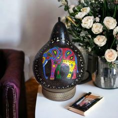 an elephant shaped vase sitting on top of a table next to flowers and a book