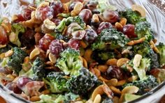 a bowl filled with broccoli, grapes and nuts