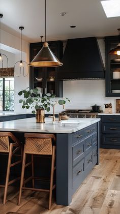 a kitchen with blue cabinets and wooden floors, two pendant lights above the island counter