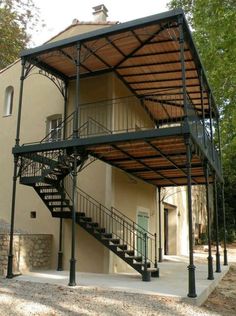 a large metal structure with stairs leading up to the second floor and another building in the background