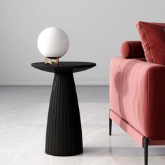 a pink chair and black table with a white ball on it next to a red couch