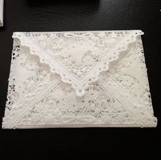 a white lace pouch sitting on top of a black table next to a cell phone