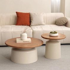 two tables sitting next to each other in front of a white couch and coffee table