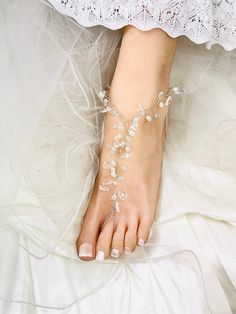 a barefoot bride's foot with white flowers and leaves on the toe, wearing a bridal garter