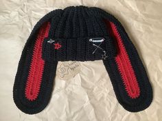 a black and red knitted hat laying on top of a white sheet