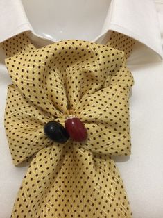 a yellow tie with black and red buttons on the front, attached to a white shirt