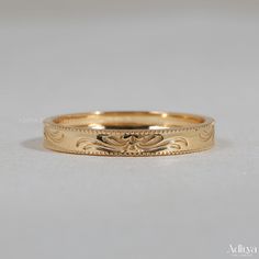 a gold wedding band with an intricate design