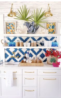 a kitchen with blue and white tiles on the wall, gold accents and brass pulls