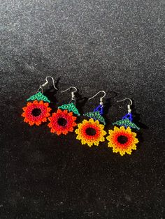 three pairs of beaded flower earrings on a black surface