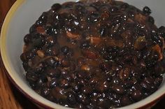 a white bowl filled with black beans on top of a wooden table