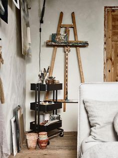 a living room filled with furniture next to a painting easel and other art supplies