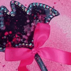 a tiara with pink and blue glitters on it, tied to a pink ribbon