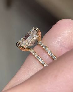 a woman's hand with a diamond ring on top of her finger and an engagement band in the middle