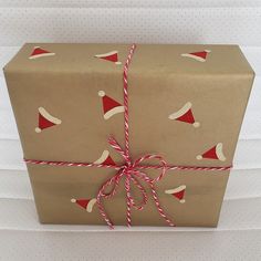 a present wrapped in brown paper with red and white christmas hats on it's wrapper