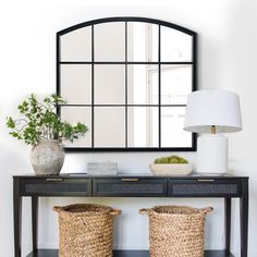 a console table with two baskets and a large mirror on the wall in front of it