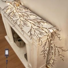 a white fireplace with branches and lights on it