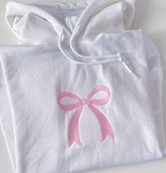 a white shirt with a pink bow on the front and back, sitting on a table