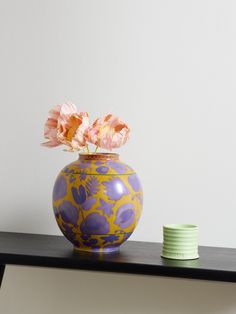 a blue and yellow vase with pink flowers in it